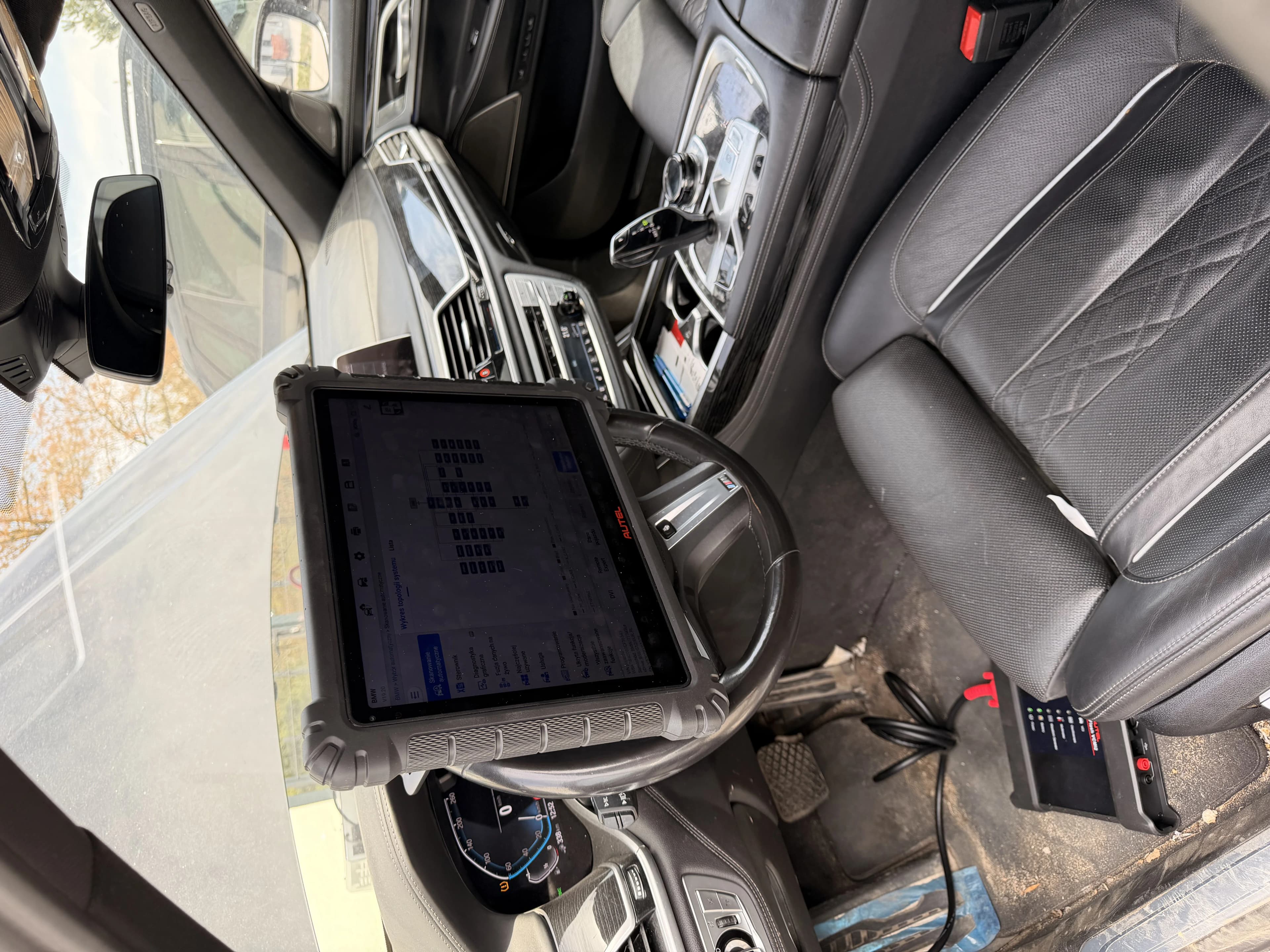 Tablet Autel MaxiSYS Ultra S2 na kierownicy BMW 745Le z listą wyników autoscanu — sesja 1 diagnostyki